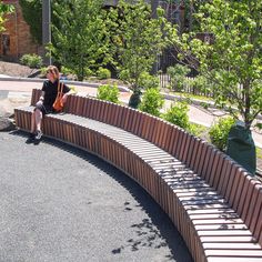 a woman sitting on top of a wooden bench