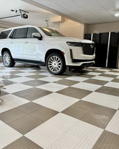 a white suv parked in a garage with black and white checkered tile flooring