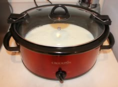 a crock pot with milk in it sitting on the stove