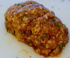 a piece of meat covered in sauce and parsley on top of a white plate