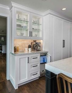 a kitchen with white cabinets and wooden floors