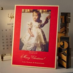 a red and white photo frame sitting on top of a shelf next to a calendar