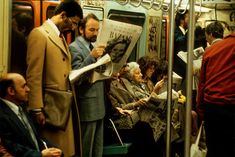 people are sitting on the subway and reading newspapers while others look at them in the distance