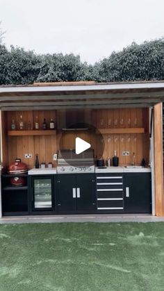 an outdoor kitchen with cabinets and cooking utensils on the outside, surrounded by grass