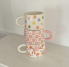 three mugs stacked on top of each other with hearts and flowers painted on them