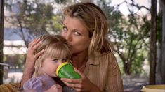 a woman holding a child while they both blow dry their hair with a green and yellow cup