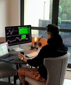 a person sitting at a desk with a laptop and computer monitor in front of them