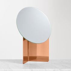 a round mirror sitting on top of a white counter next to a metal stand with a circular mirror on it