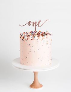 a pink cake topped with sprinkles and a mr and mrs topper