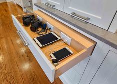 an open drawer in a kitchen with two electronic devices on the counter and other electronics