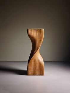 a wooden vase sitting on top of a gray floor in front of a wall with light coming through it