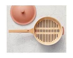 a wooden spatula next to a pink pot on a white surface with a lid