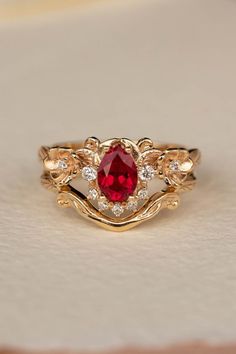 a gold ring with a red stone surrounded by diamonds