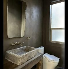 a bathroom with a toilet, sink and mirror in it's corner next to a window