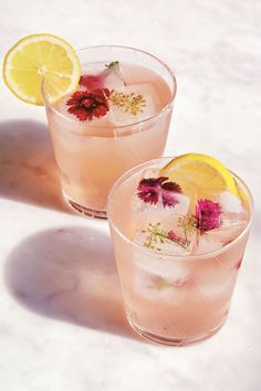 two glasses filled with pink lemonade and garnished with wildflowers on the rim