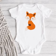 a white bodysuit with an orange fox on it, next to a tassel