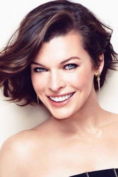 a woman with blue eyes smiling and wearing a strapless top on her head, in front of a white background