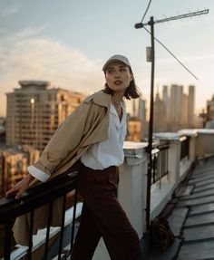 a woman standing on top of a roof next to a street light and tall buildings