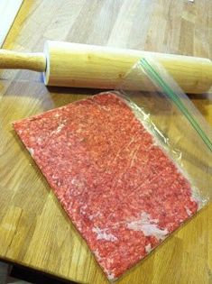 a piece of raw meat sitting on top of a wooden table next to a rolling pin