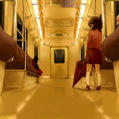 a woman in a red dress walking down a train aisle with an umbrella over her head