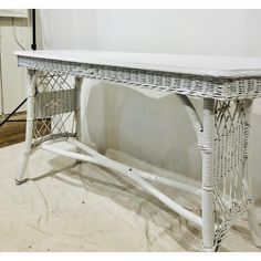 a white table with wicker baskets on it's legs and a shelf underneath