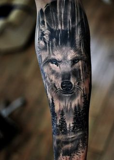 a man's arm with a wolf tattoo on it and trees in the background