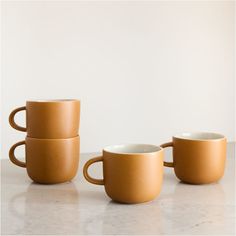 three coffee mugs sitting next to each other on top of a white countertop