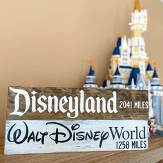 a wooden sign sitting on top of a table in front of a disney world castle