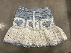 a crocheted skirt with hearts on the front and bottom, sitting on a floor