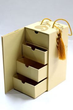 an open box with three drawers and a tassel