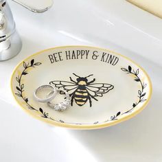 a bee happy and kind ring dish on a bathroom sink