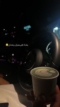 a person holding up a cup of coffee in their hand while sitting in a car