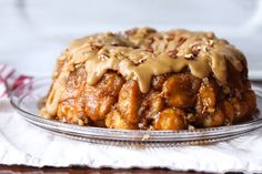 a bundt cake covered in caramel and pecans on a glass platter