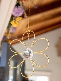 a gold flower hanging from the ceiling with a crystal bead in it's center