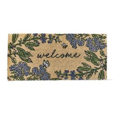 a welcome door mat with blue flowers and green leaves on the front, which says welcome