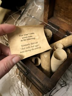 a person holding up a piece of paper with writing on it in a wooden box