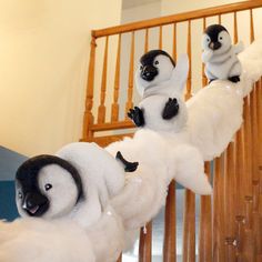 three stuffed penguins sitting on top of white fluffy balls in front of a stair case