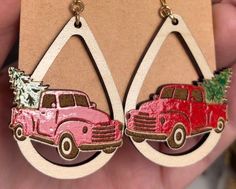 a pair of pink and red trucks are hanging from wooden hoop earrings with christmas trees on them