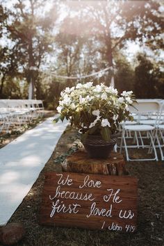 a wooden sign that says we love because he first loved us with flowers in it