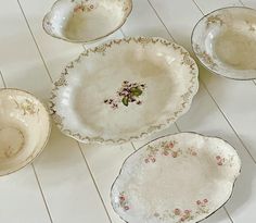 four white dishes sitting on top of a counter next to each other with flowers painted on them