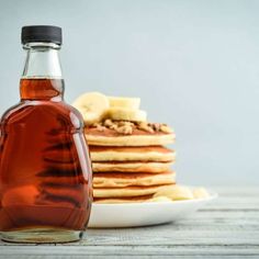 a bottle of syrup next to pancakes on a plate