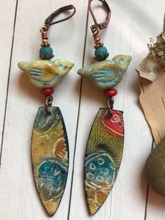 The whimsical colors and patterns in this pair feature polymer clay drops by Tsin Designs and a golden Czech glass bird with a turquoise wash. This one of a kind pair of earrings are lightweight, and measure 3 inches long. Copper findings and lever back ear wires. Whimsical Bird Design Jewelry For Gifts, Bohemian Dangle Clay Jewelry, Hand Painted Artsy Turquoise Earrings, Colar Hippie, Clay Bird Earrings, Bohemian Turquoise Polymer Clay Earrings, Turquoise Bohemian Polymer Clay Earrings, Copper Bird Earrings, Bohemian Patina Earrings