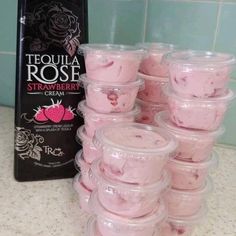 several plastic containers filled with pink jello sitting on top of a counter next to a bottle