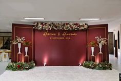 a red wall with flowers and candles on it in front of a white carpeted floor