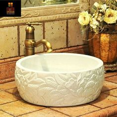 a white bowl sink sitting on top of a counter next to a vase with flowers