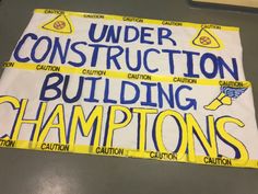 a sign that says under construction, building championships and cautions on the side of a table