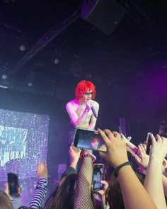 a woman with red hair is on top of someone's shoulders at a concert