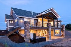 a two story house is lit up at night with lights on the windows and balcony