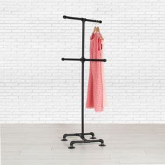 a coat rack with two coats hanging from it's sides and a pink sweater on top