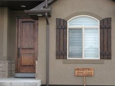 a brown house with shutters and a wooden sign